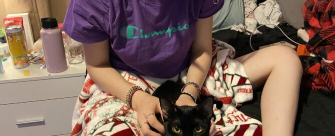 Clarice sitting on the floor with her human sister. Snuggling on a blanket between her legs.