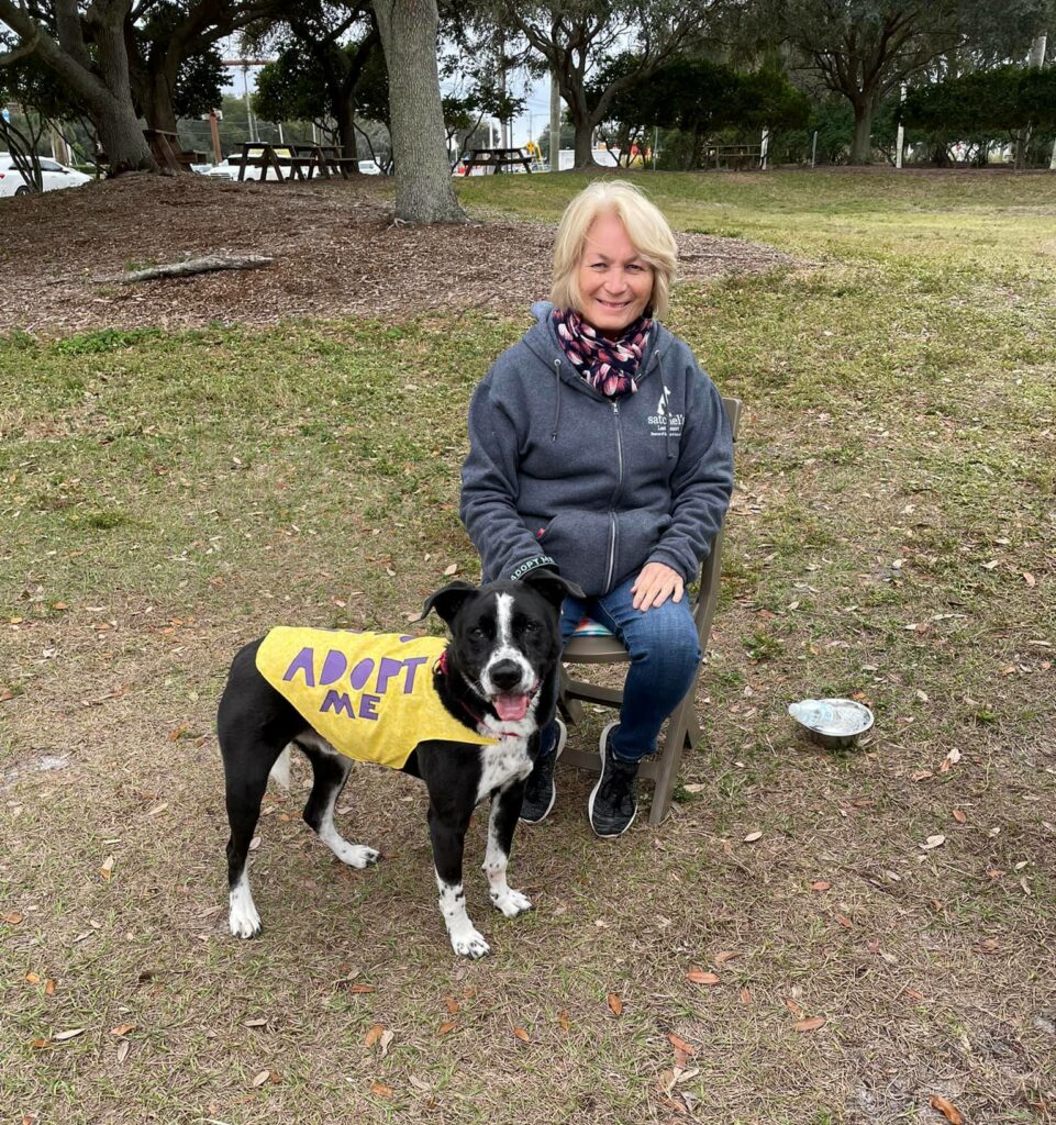 Cooper with his adopt be vest on, standing beside his Woof Pack leader, Kathy.