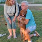 Winston posting for his adoption picture with his new mom and dad. Looking straight at the camera.