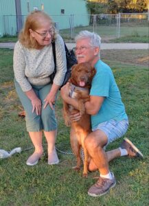 Winston posting for his adoption picture with his new mom and dad. Looking straight at the camera.