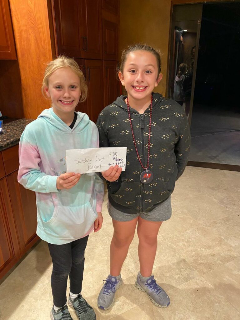 Audrey and Zoe smiling holding the envelope of money.