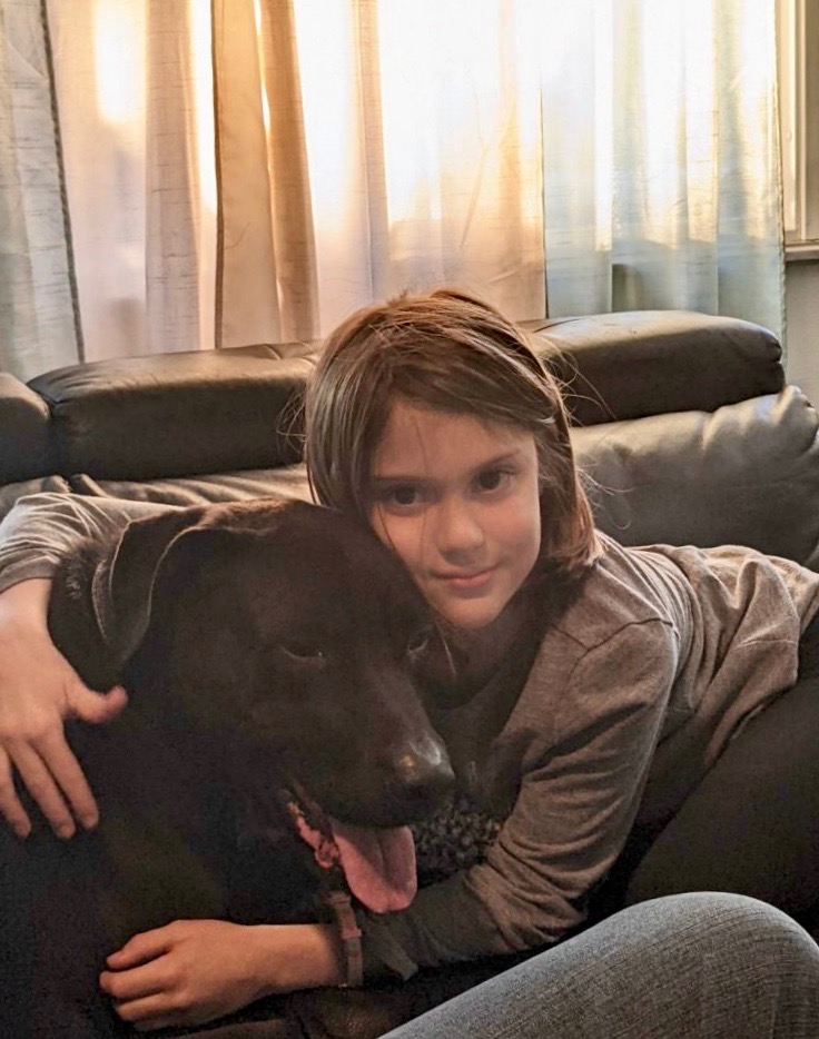 Cooper being hugged by his new little person on the couch.