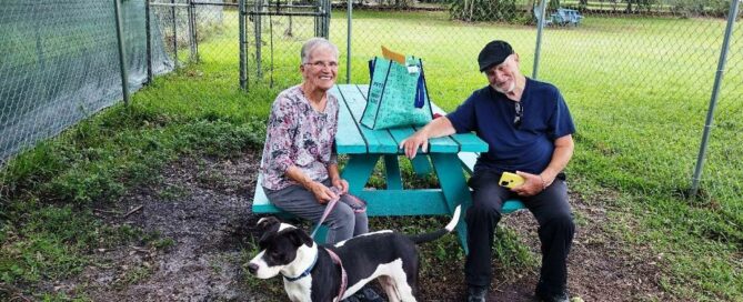 Kya standing beside the picnic table at Satchel's with is new mom and dad.