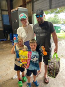 Colton holding a bag of treats with his family holding other donations.