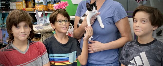 Stella in the arms of her new mom, human siblings standing beside.