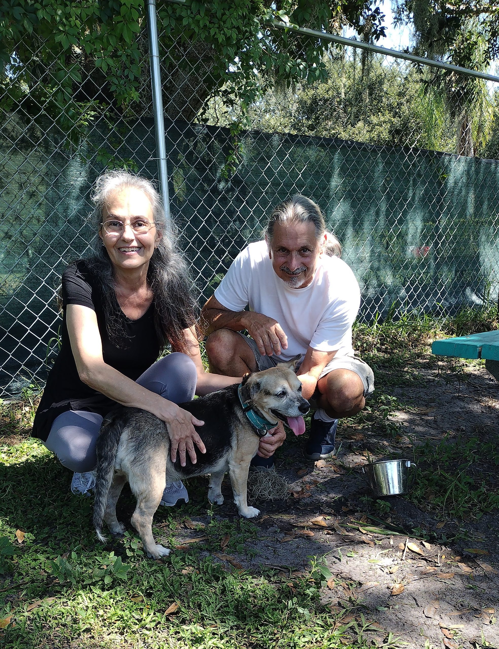 Dakota standing with his new mom and dad (squatting beside him) in the yard at Satchel's.