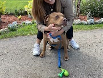 Sheri (adopter) bending over hugging Nakoma at Satchel's.