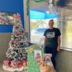 Holiday box with dog cutout and employee standing beside in the lobby at Eager Beaver Cash Wash on Beneva.