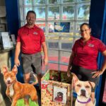 Holiday box with dog cutout and 2 employees standing beside in the lobby at Eager Beaver Cash Wash in Fort Myers