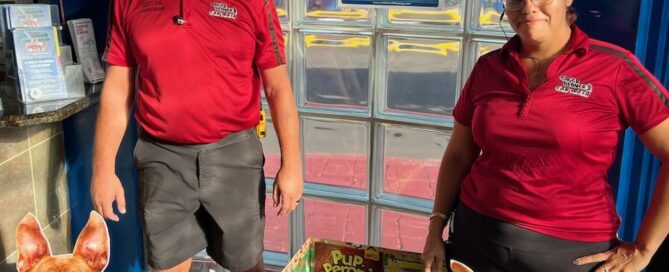 Holiday box with dog cutout and 2 employees standing beside in the lobby at Eager Beaver Cash Wash in Fort Myers