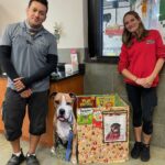 Holiday box with dog cutout and 2 employees standing beside in the lobby at Eager Beaver Cash Wash in Venice..