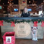 Oak and Stone employee behind the holiday decorated bar. Winston and the holiday box in front.