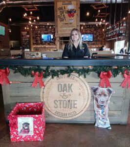 Oak and Stone employee behind the holiday decorated bar. Winston and the holiday box in front.