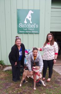 Tax Collector staff at Satchel's with Michal Anne, Director of Operations, and ZigZag with donations behind.