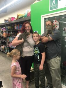Hadley and Hudson in mom and dad's arms with kids by their side outside the adoption room at Pet Supplies Plus.