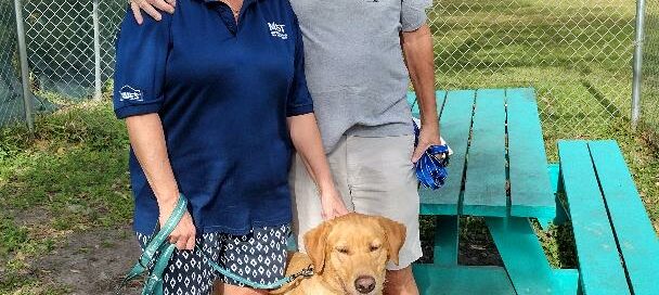 Titan standing outside Satchel's with his new mom and dad.