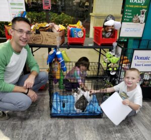 Mario and Yoshi in a crate with dad and kids beside at Pet Supermarket.