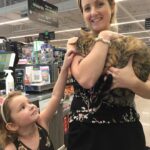 Mitzie in the arms of her new mom at the store, with new human sister by their side.