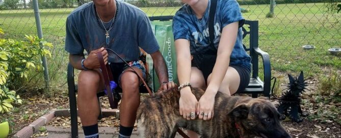 Dottie outside Satchel's with her new family sitting on the bench behind her.