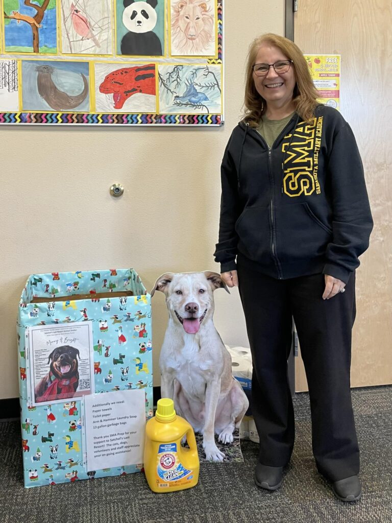 SMA Prep staff member standing beside our donation box and dog cutout.