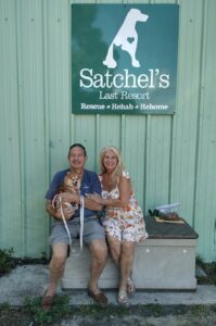 Muffin sitting on her dad's lap, mom beside, outside Satchel's.